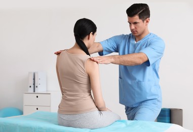 Photo of Orthopedist examining woman in clinic. Scoliosis treatment