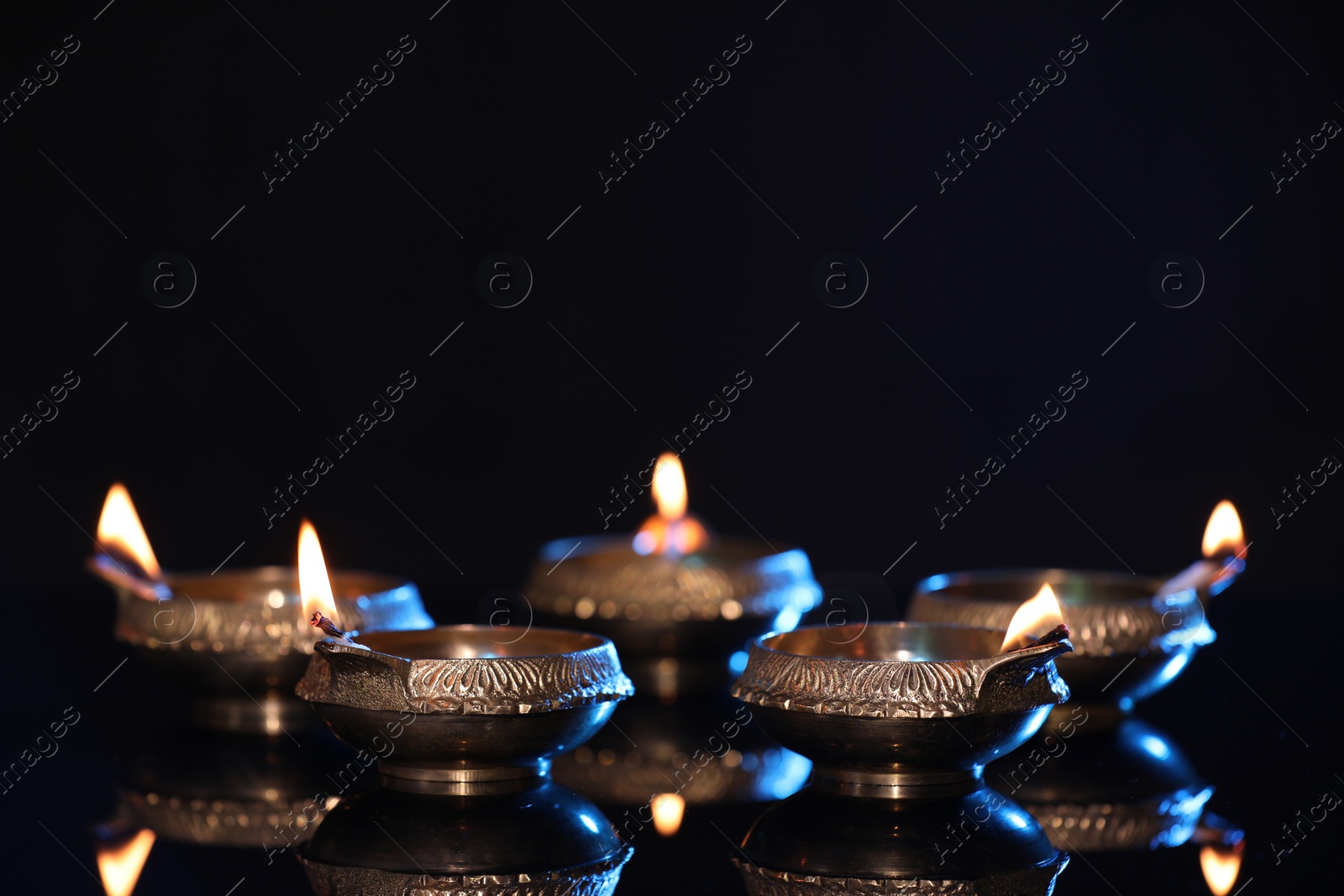 Photo of Many lit diyas on black background, space for text. Diwali lamps