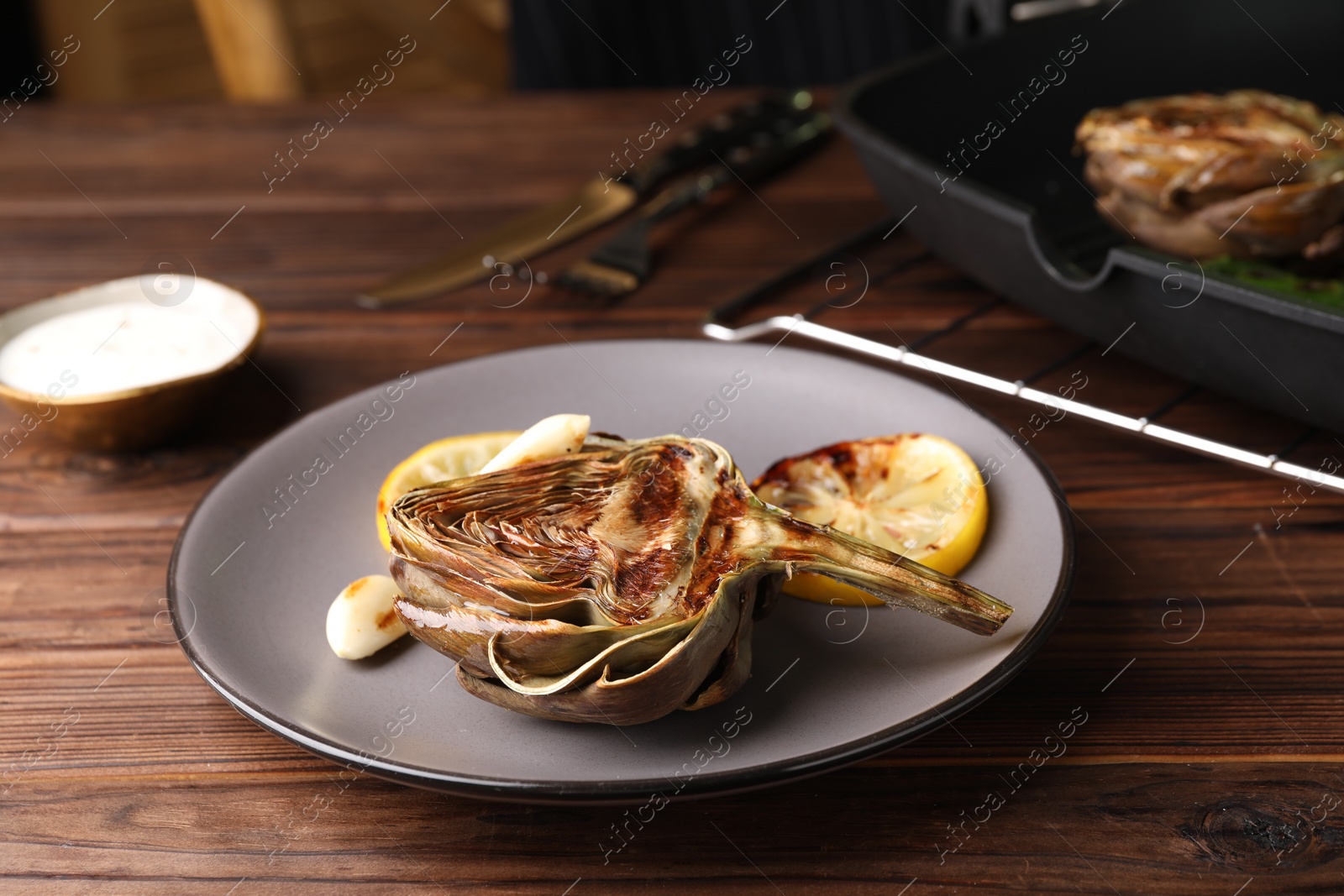 Photo of Tasty grilled artichoke served on wooden table, closeup