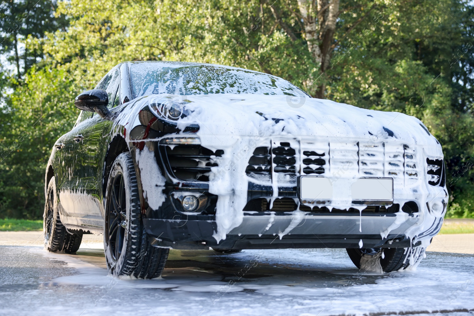 Photo of Auto covered with cleaning foam at outdoor car wash