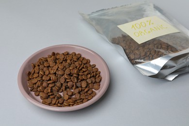 Photo of Plate and pack of organic kibble on light background