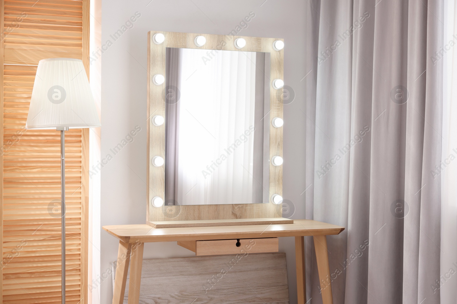 Photo of Beautiful mirror with light bulbs and lamp in makeup room