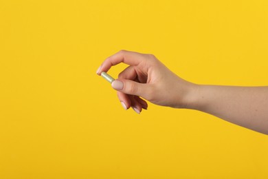 Photo of Woman holding vitamin pill on yellow background, closeup. Health supplement