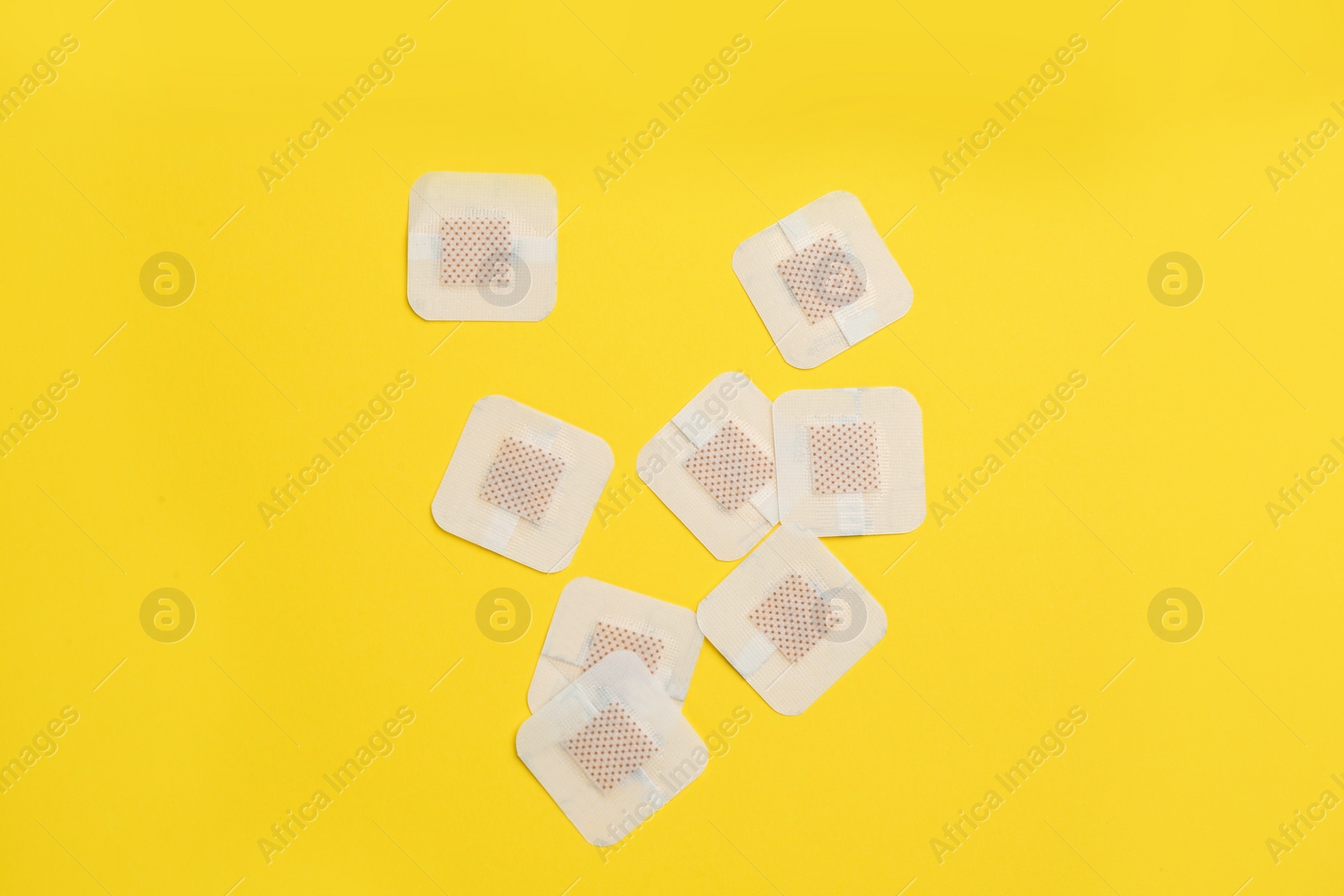 Photo of Sticking plasters on yellow background, flat lay