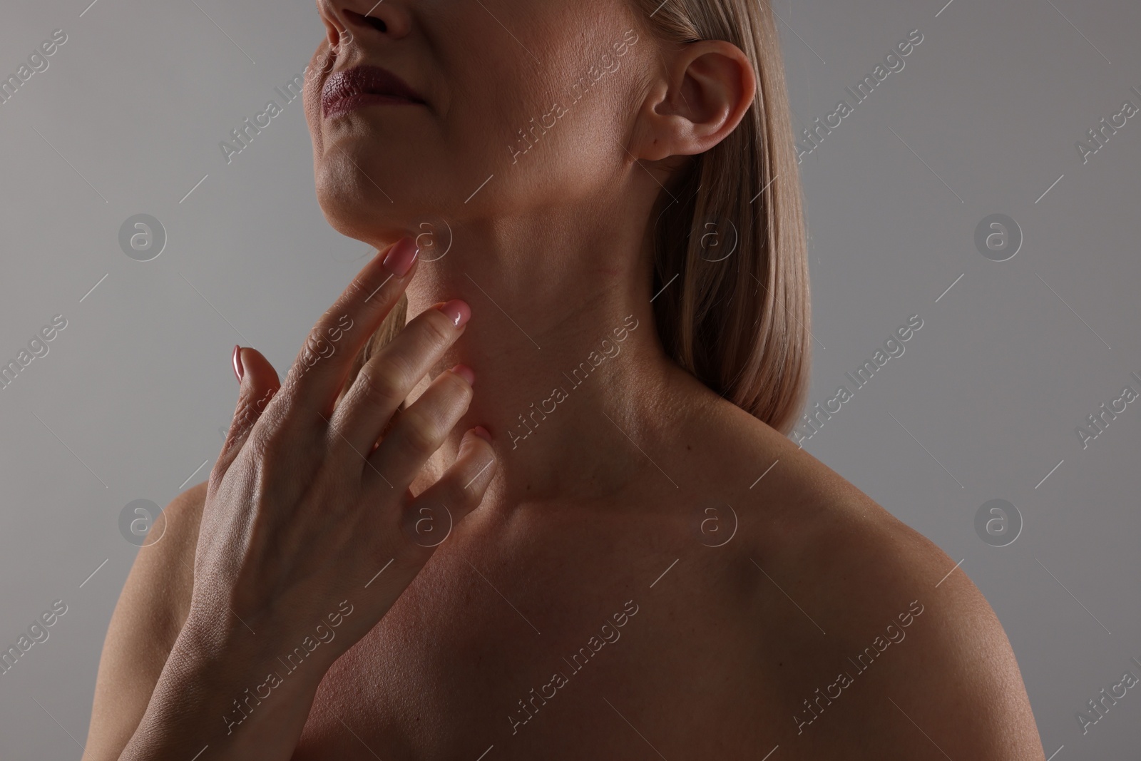 Photo of Woman touching her neck on grey background, closeup