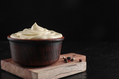 Photo of Fresh mayonnaise sauce in bowl on black table, closeup. Space for text