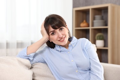Photo of Portrait of beautiful young housewife on sofa at home