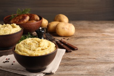 Bowl of tasty mashed potatoes with black pepper served on wooden table. Space for text