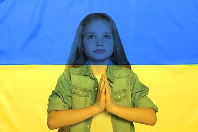 Double exposure of national flag and little girl praying. Stop war in Ukraine