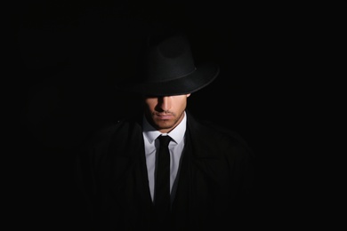 Photo of Old fashioned detective in hat on dark background