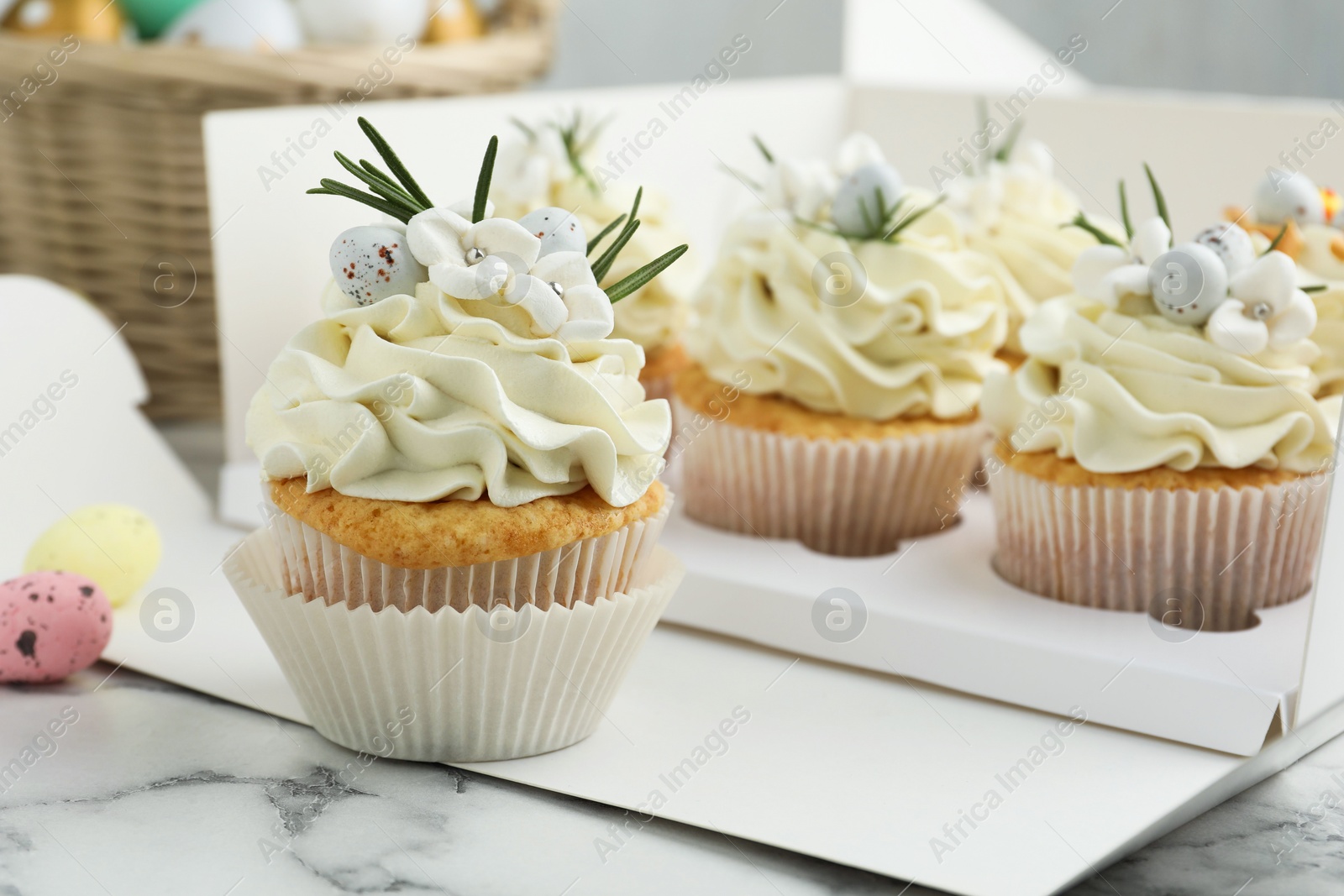 Photo of Tasty Easter cupcakes with vanilla cream on white marble table