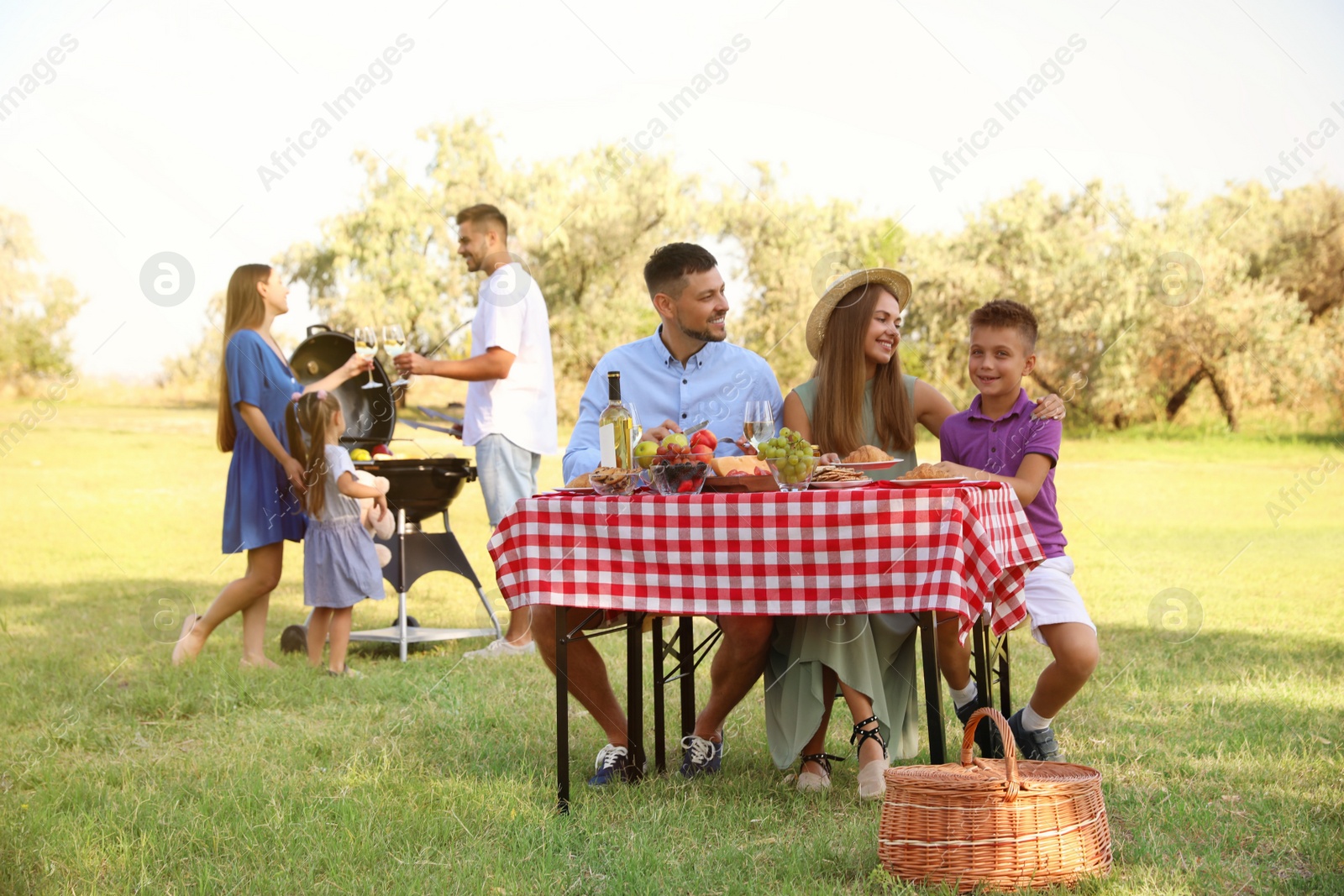 Photo of Happy families with little children having picnic in park