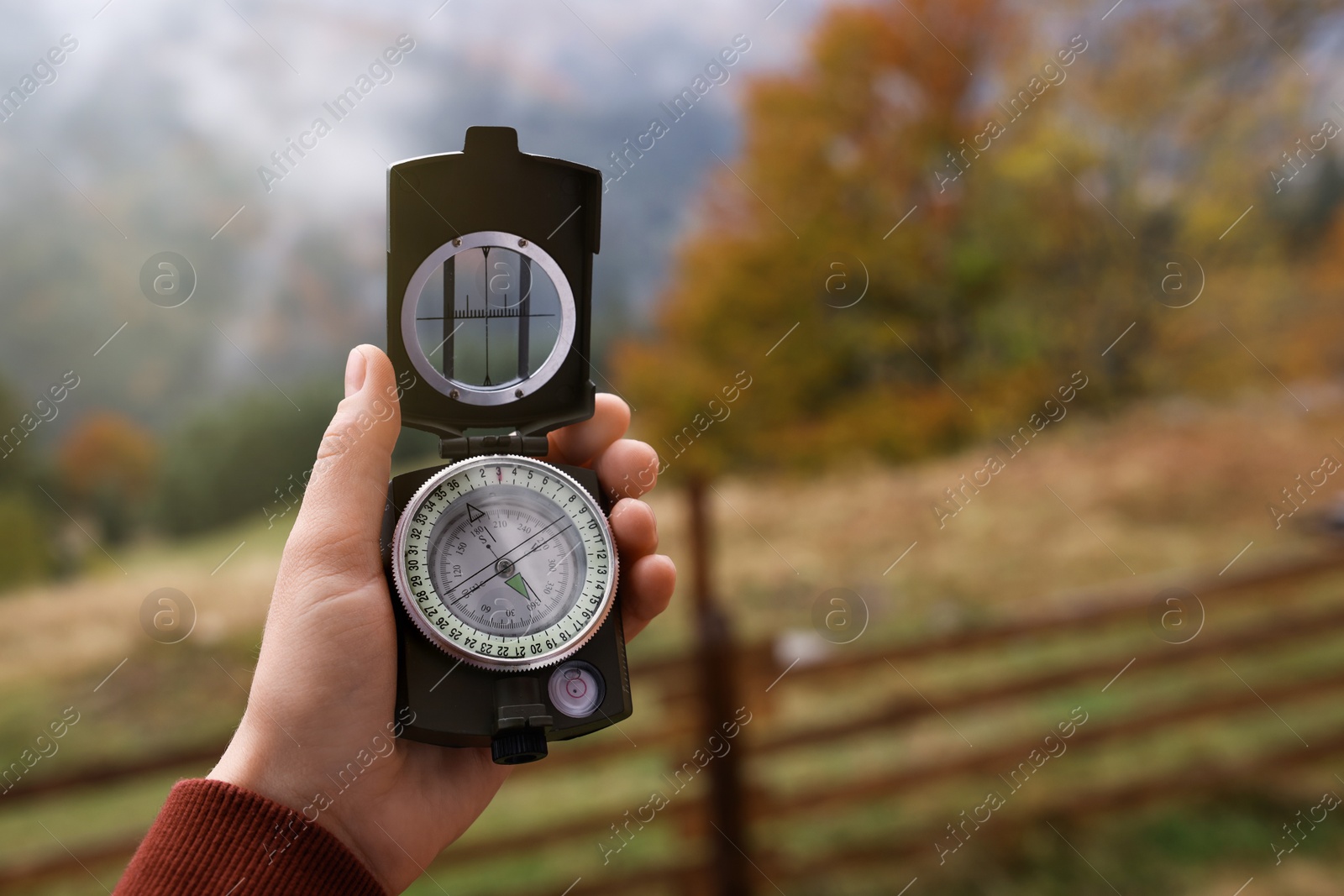 Photo of Woman using compass during journey in mountains, closeup. Space for text