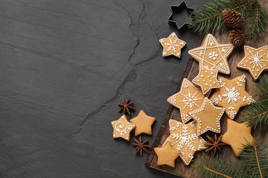 Photo of Tasty Christmas cookies, fir branches, cones and anise on black table, flat lay. Space for text