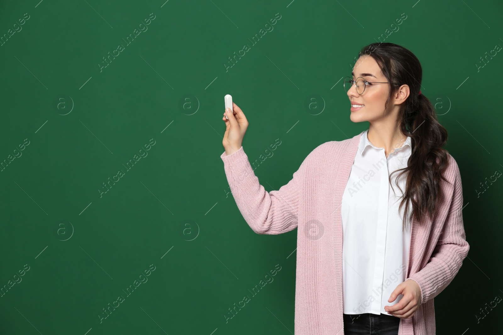 Photo of Portrait of beautiful young teacher near chalkboard, space for text