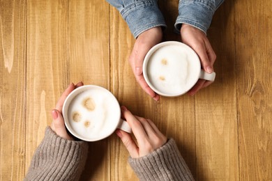 Photo of Women having coffee break at wooden table, top view