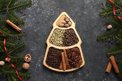 Different spices, nuts and fir branches on dark gray textured table, flat lay