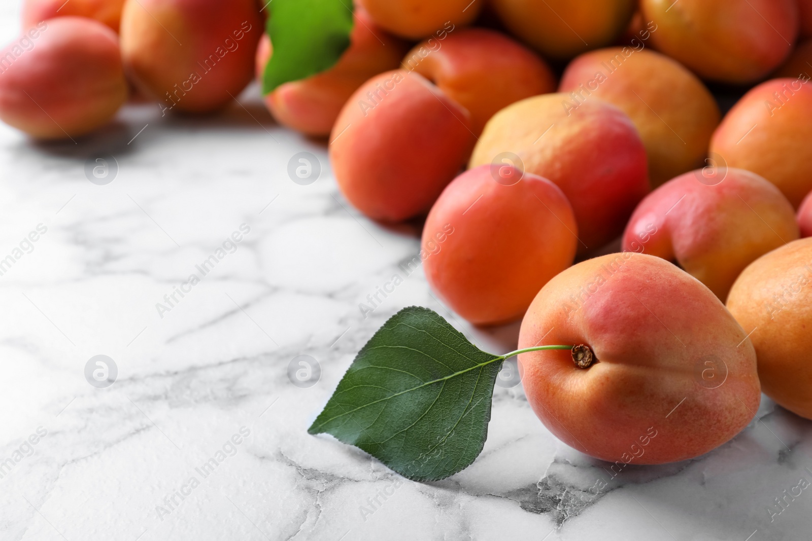 Photo of Many fresh ripe apricots on white marble table. Space for text