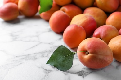 Many fresh ripe apricots on white marble table. Space for text