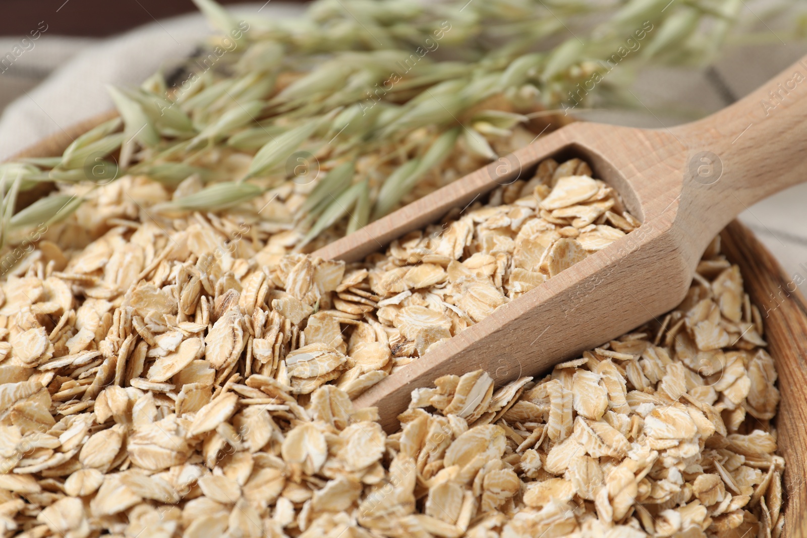 Photo of Wooden scoop with oatmeal and florets in bowl, closeup