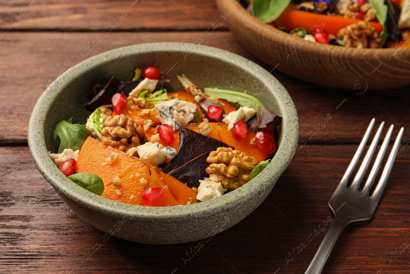 Photo of Delicious persimmon salad with cheese and pomegranate served on wooden table