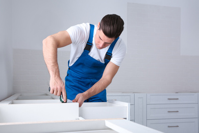 Photo of Maintenance worker installing new kitchen furniture indoors