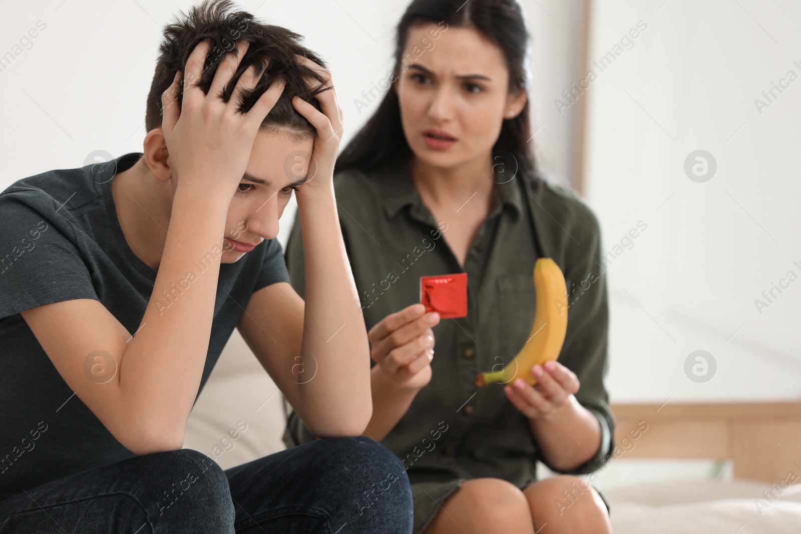 Photo of Mother talking with her teenage son about contraception at home. Sex education concept