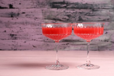 Photo of Cocktail glasses of delicious fresh watermelon juice on light wooden table. Space for text