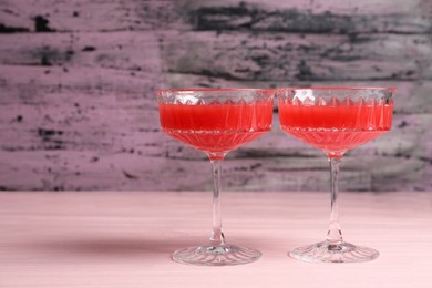 Cocktail glasses of delicious fresh watermelon juice on light wooden table. Space for text