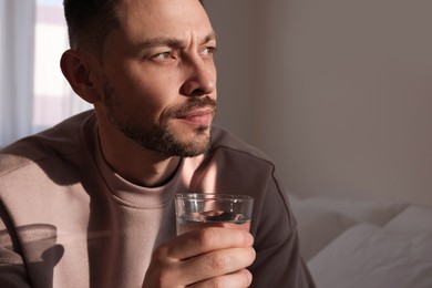 Photo of Upset man with glass of water at home. Loneliness concept