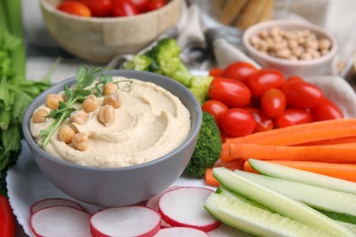 Plate with delicious hummus and fresh vegetables on table