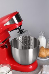 Photo of Modern red stand mixer, croissant and ingredients on gray marble table