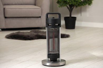 Photo of Modern infrared heater on white wooden floor in cozy room