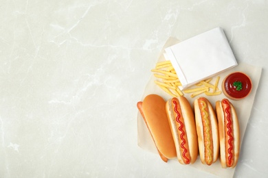Photo of Composition with hot dogs, french fries and sauce on table, top view. Space for text