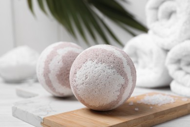 Bath bombs, sea salt and rolled towels on white wooden table, closeup