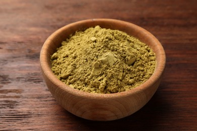Photo of Bowl of henna powder on wooden table