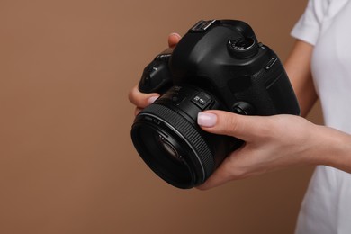 Photographer with camera on brown background, closeup. Space for text