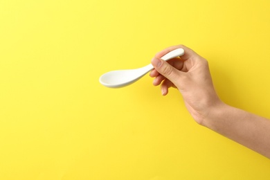 Photo of Woman holding empty miso soup spoon on color background, closeup. Space for text