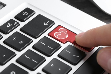 Image of Woman pressing love button on laptop keyboard, closeup. Online dating site