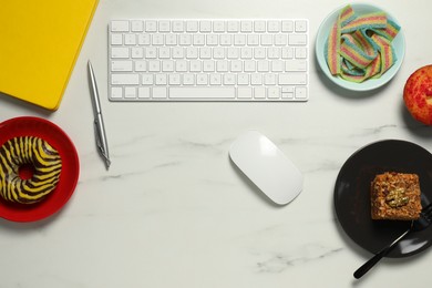 Photo of Bad eating habits at workplace. Keyboard and different snacks on white marble table, flat lay with space for text