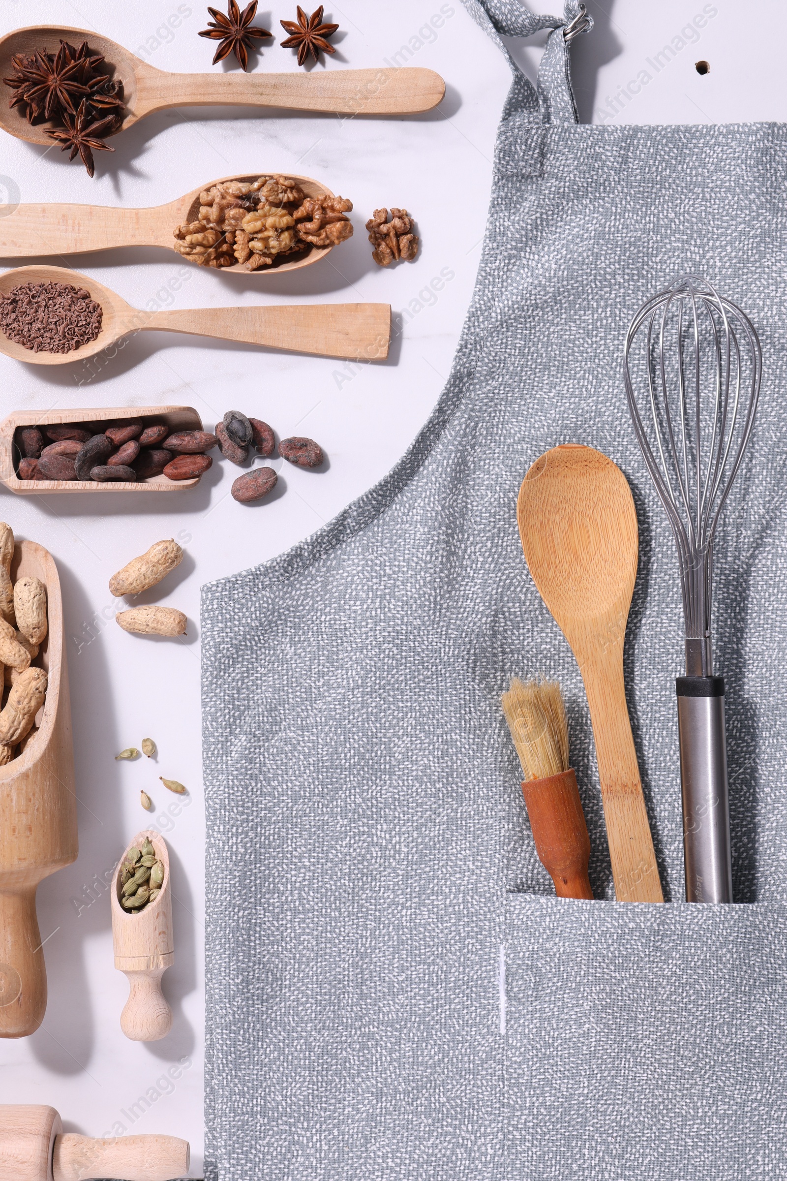 Photo of Flat lay composition with grey apron, ingredients and kitchen utensils on white table