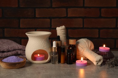 Photo of Aromatherapy. Scented candles and spa products on gray textured table