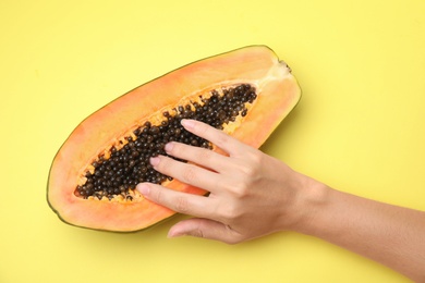 Photo of Young woman touching half of papaya on yellow background, top view. Sex concept