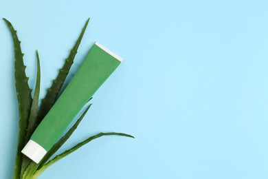 Tube of toothpaste and fresh aloe on light blue background, flat lay. Space for text