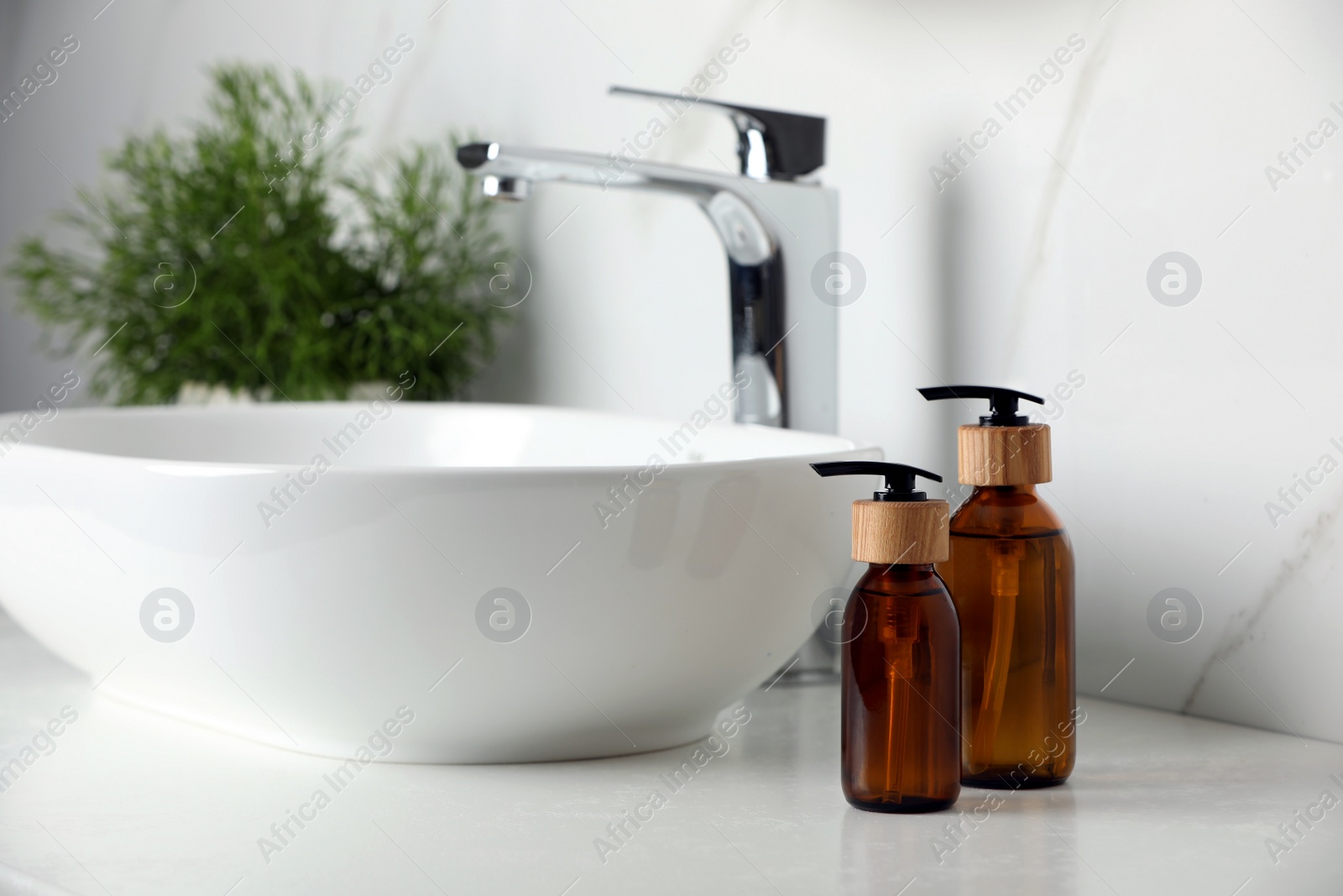 Photo of Bottles with dispenser caps on white table in bathroom