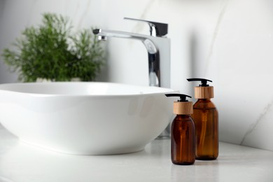 Photo of Bottles with dispenser caps on white table in bathroom