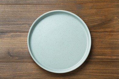 Empty ceramic plate on wooden table, top view