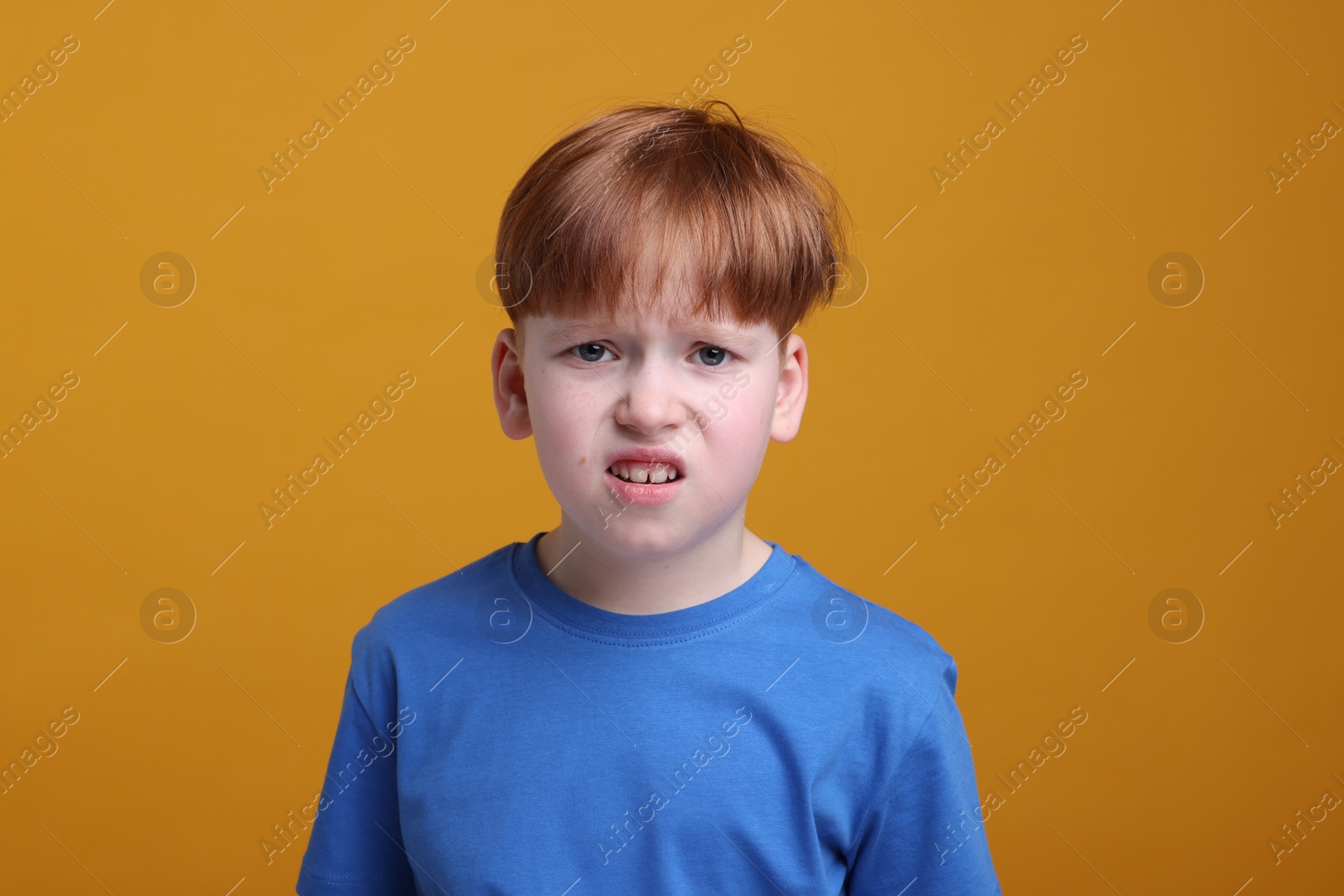 Photo of Portrait of surprised little boy on orange background