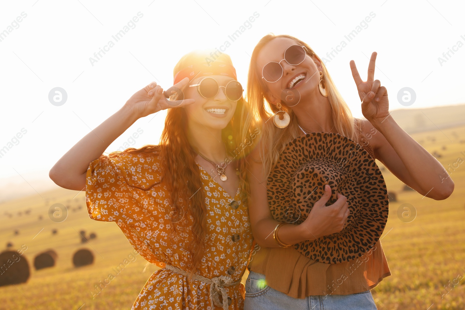 Photo of Beautiful happy hippie women showing peace signs in field