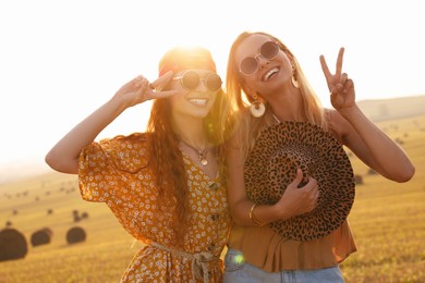 Photo of Beautiful happy hippie women showing peace signs in field